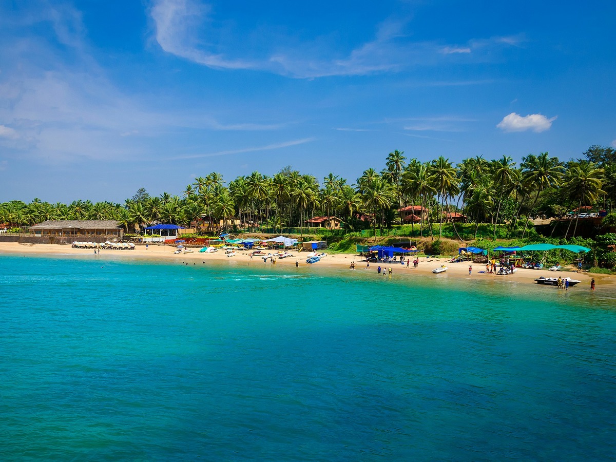 Beautiful sandy beach with palm trees and clear blue waters in Goa, India